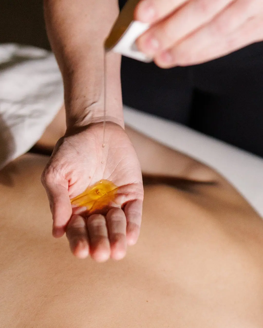 Therapist's hands applying oil before a massage