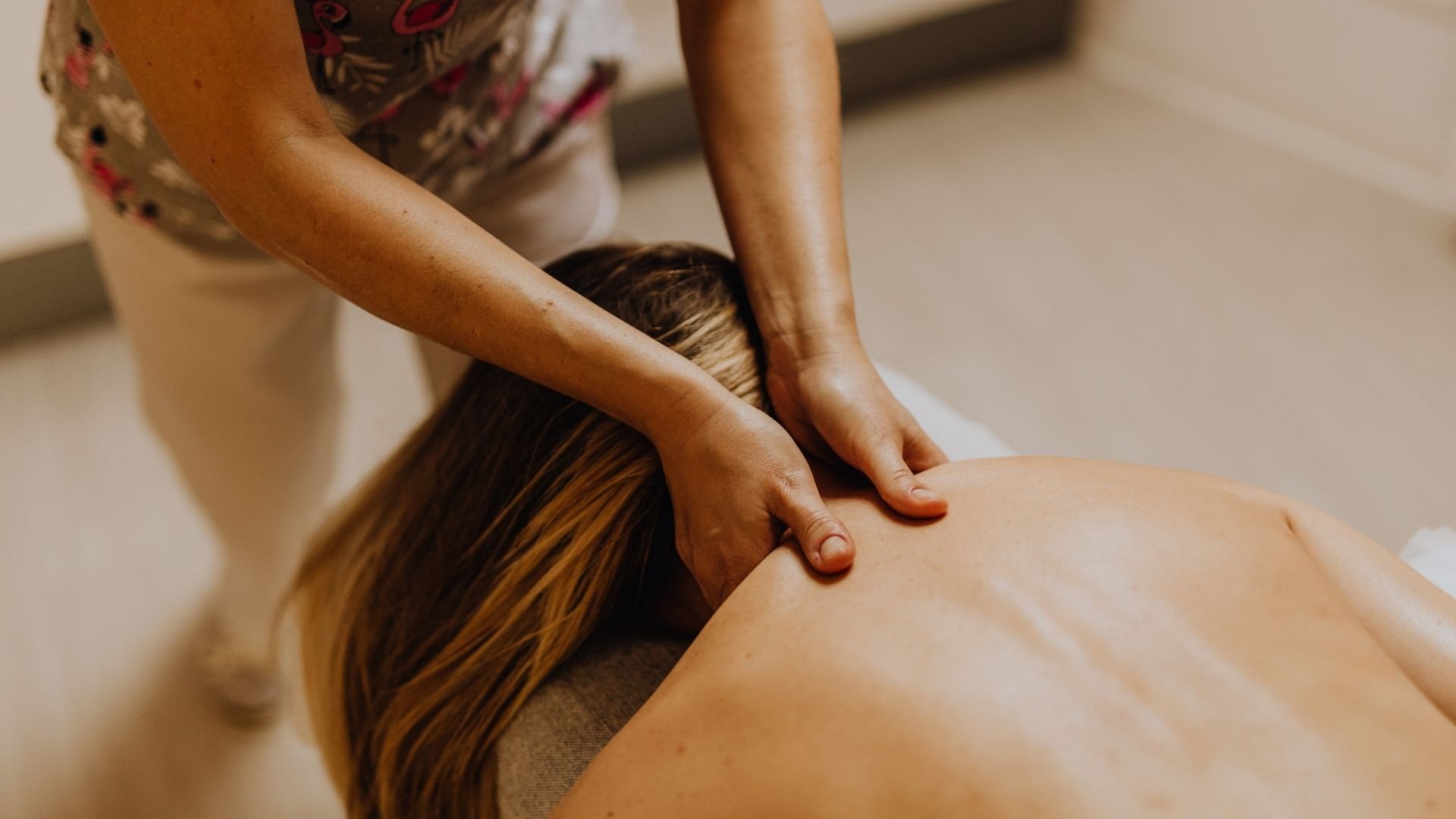Massage therapist applying therapeutic massage to client's back during wellness treatment session.