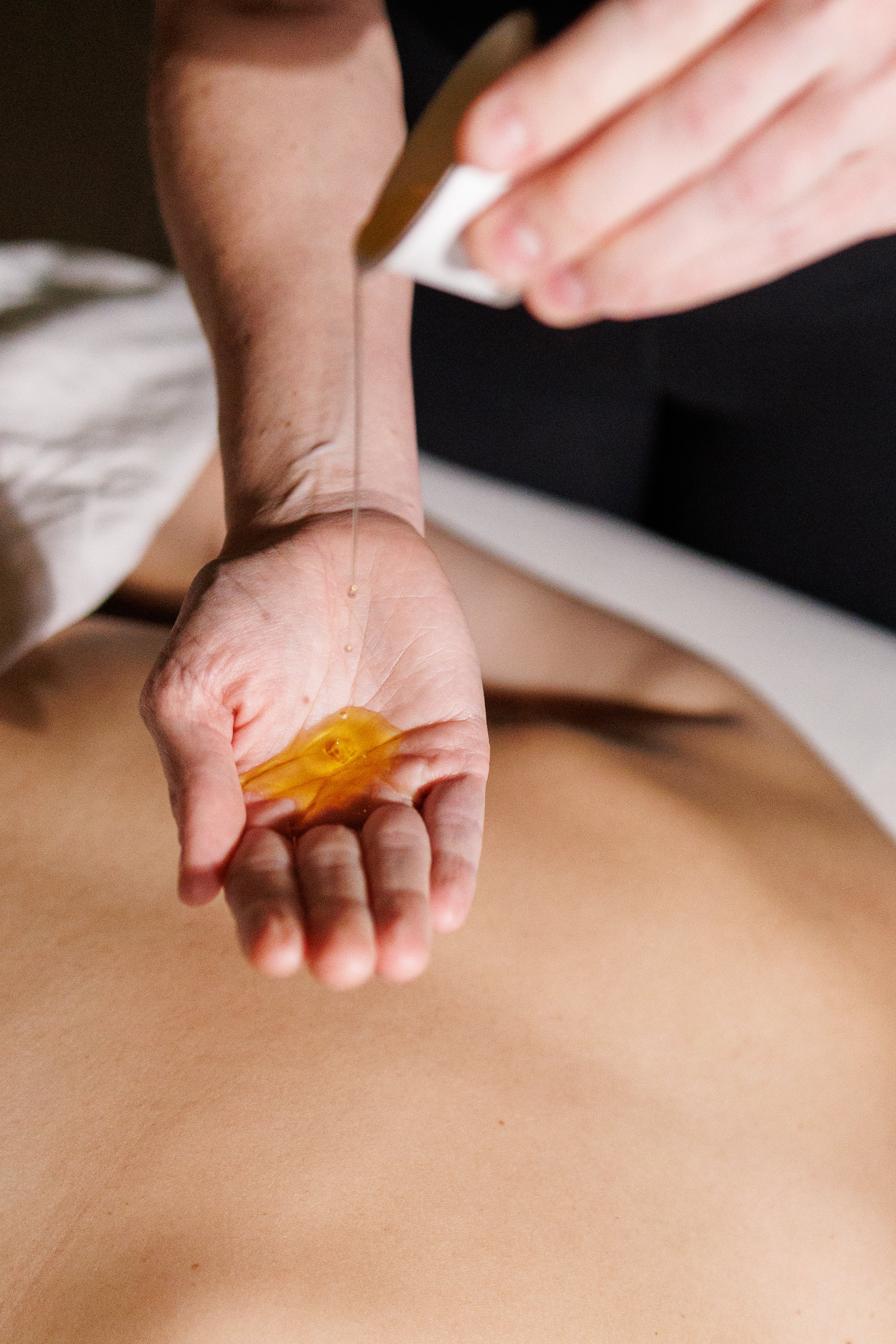 Child's hand holding a small amber stone or crystal during massage therapy session
